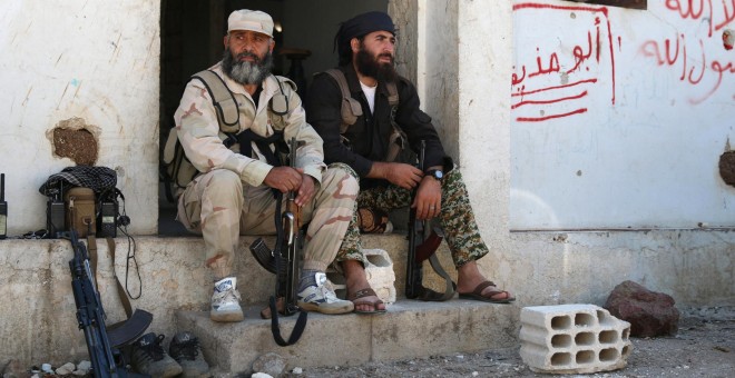 Dos milicianos rebeldes descansan junto a sus armas en la gobernación de Quneitra. - REUTERS