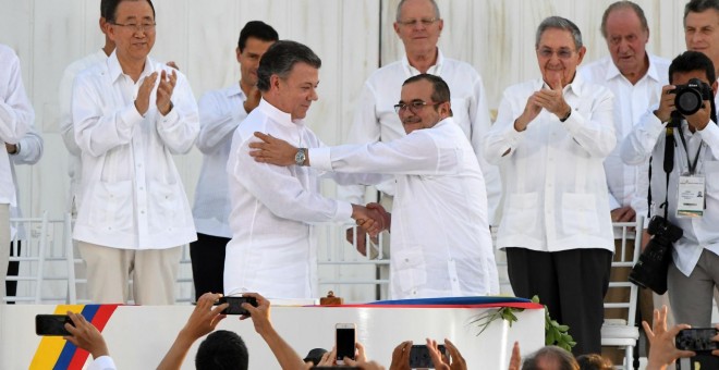 El presidente de Colombia, Juan Manuel Santos, estrecha la mano al máximo líder de las FARC, Rodrigo Londoño Echeverri, alias 'Timochenko', tras firmar los Acuerdos de Paz. - AFP