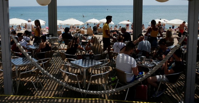 Turistas en un chiringuito en la playa de la Barceloneta, en Barcelona. REUTERS