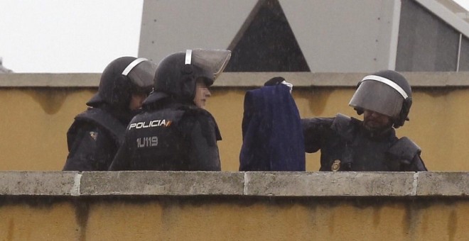 Efectivos de la Policía Nacional permanecen en la azotea del Centro de Internamiento de Extranjeros (CIE) de Aluche, en Madrid, donde anoche se encerraron unos cuarenta inmigrantes. EFE/Paco Campos