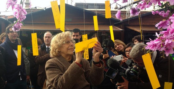 La alcaldesa de Madrid, Manuela Carmena, escribe 'Que se acabe la guerra en Siria' en un árbol de los deseos./ J. Y.