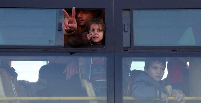 Varias personas saludan desde el autobús con el que van a ser evacuados de Alepo. - AFP