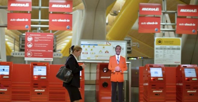 Una mujer pasa junto a los terminales de facturación de Iberia en la Terminal T4 del aeropuerto de Barajas. AFP/Pedro Armestre