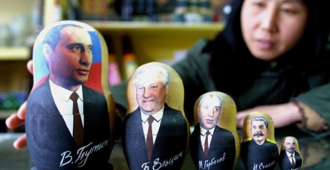 Una tendera china enseña una colección de muñecas matrioskas con las caras de Putin, Yeltsin, Gorbachov, Stalin y Lenin.- AFP