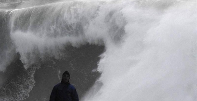 Un hombre camina cerca de las olas esta tarde en la costa de Muxía (A Coruña). | LAVANDEIRA JR. (EFE)