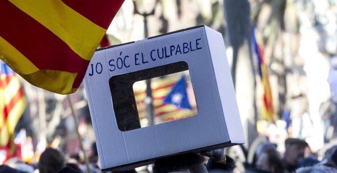 Una persona lleva una urna reivindicativa en apoyo al expresidente Artur Mas, la exvicepresidenta Joana Ortega, y la exconsellera Irene Rigau, durante la concentración de apoyo en su recorrido a pie desde el Palau de la Generalitat hasta el Tribunal Super