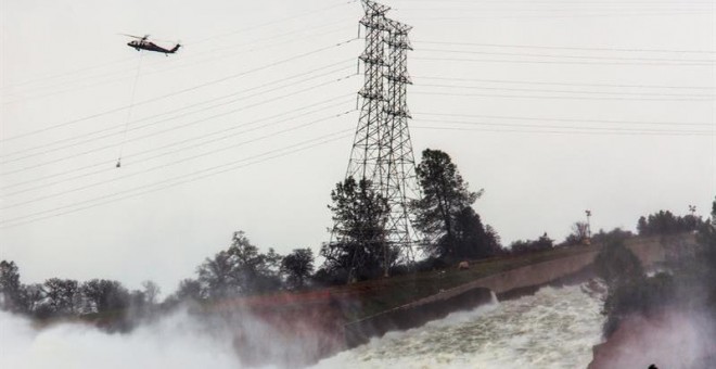 Un helicóptero sobrevuela la presa Oroville y el río Feather con sacos cargados de rocas para aliviar la emergencia ocasionada por la erosión del desagüe en la represa Oroville hoy, lunes 13 de febrero de 2017, en Oroville, California (EE.UU.). Los trabaj