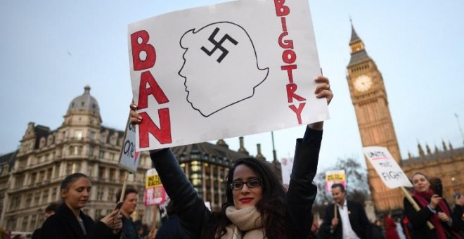 Una manifestante sujeta una pancarta en contra de las políticas antiinmigración de Trump. - AFP