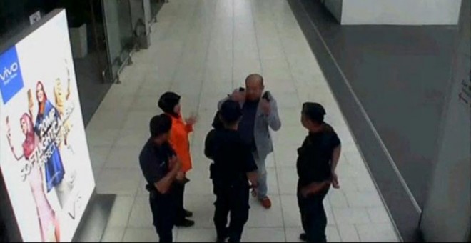 Kim Jong-nam, con traje gris, habla con agentes de seguridad del aeropuerto de Kuala Lumpur el día que fue intoxicado por el veneno VX. | REUTERS