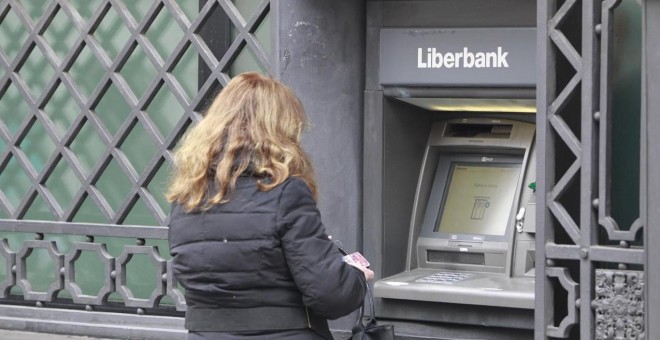Una mujer opera un cajero automático en una oficina de Liberbank. E.P.