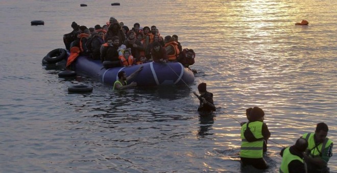 Voluntarios de una ONG ayudan a refugiados y migrantes que llegan en una lancha neumática a la costa de Mytilini, en la isla de Lesbos (Orestis Panagiotou / EFE)