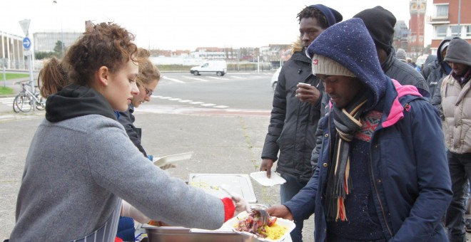 Varios refugiados esperan en la cola para recibir comida / ENRIC BONET