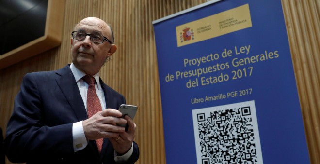 El ministro de Hacienda, Cristóbal Montoro, se prepara para escanear con el móvil el código QR del proyecto de Ley de Presupuestos Generales del Estado (PGE) para 2017. REUTERS/Juan Medina