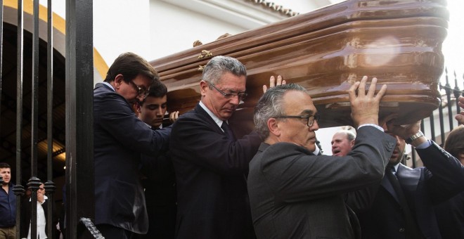 El exministro de Justicia, Alberto Ruiz Gallardón, yerno del fallecido José Utrera Molina porta junto a otros allegados el féretro del que fuera ministro en la época franquista, mientras os asistentes cantan el 'Cara al Sol', en la Iglesia de San Miguel e