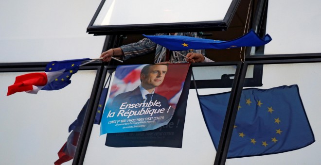 Uno de los carteles de campaña de Emmanuel Macron rodeado de banderas de la Unión Europea.- REUTERS