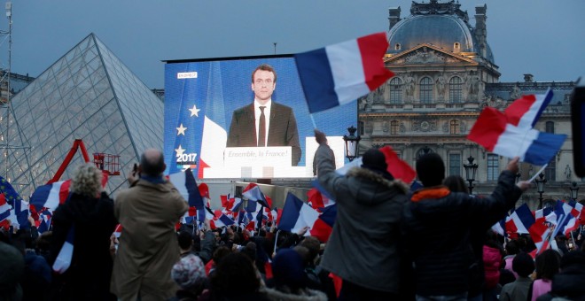 Los seguidores de Emmanuel Macron siguen en una pantalla gigante la primera intervención del presidente electo francés, en la explanada del Museo del Louvre, donde se celebra su victoria en las presidenciales. REUTERS/Jean-Paul Pelissier