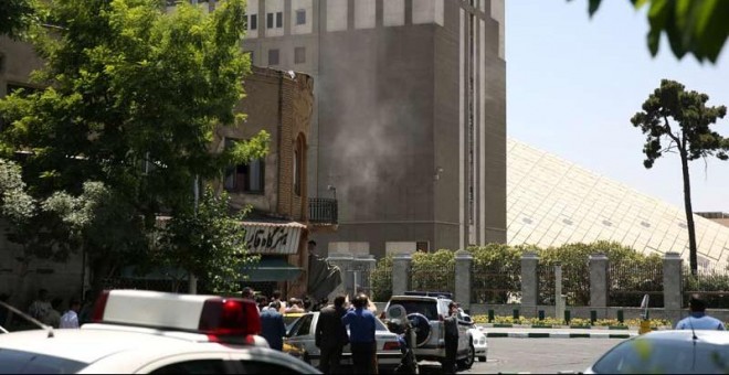 Fuerzas de seguridad permanecen en el exterior del edificio del Parlamento iraní, de donde se ver salir humo. | REUTERS