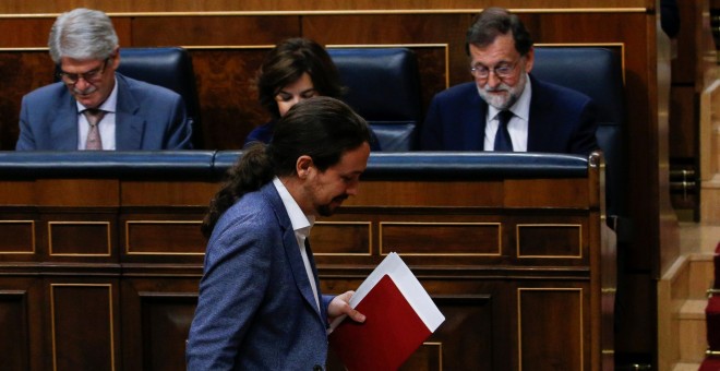 El líder de Podemos, Pablo Iglesias, pasa por delante del presidente del Gobierno, Mariano Rajoy, sentado en su escaño, durante la moción de censura. REUTERS/Juan Medina