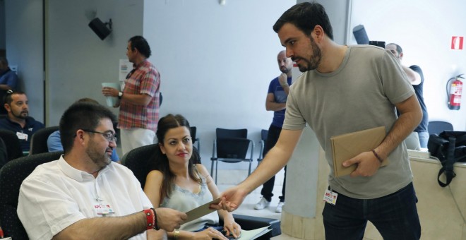 El coordinador federal de IU, Alberto Garzón, reparte invitaciones de su boda momentos antes de presentar a la asamblea federal de su formación el informe que hace balance sobre la alianza con Podemos y en el que reclama una mayor visibilidad frente al p