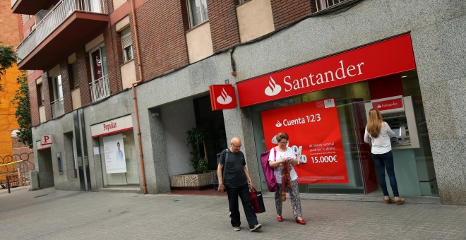 Una mujer utiliza el cajero automático de una oficina del Banco Santander, ubicado junto a un sucursal del Banco Popular, en Barcelona. REUTERS/Albert Gea