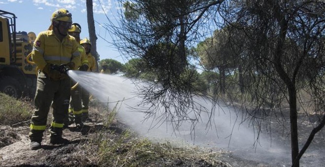 Efectivos del Infoca realizan labores de refresco tras el incendio forestal declarado el pasado sábado en el paraje 'La Peñuela' de Moguer (Huelva), que ha afectado a una amplia superficie de masa forestal del entorno de Doñana e incluso parte del parque