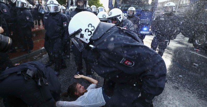 Varios agentes antidisturbios cargan contra un manifestante en Hamburgo. /REUTERS