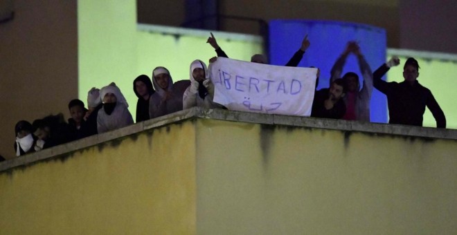 Un interno del Centro de Internamiento de Extranjeros (CIE) de Aluche, Madrid, muestra un cartel desde la azotea del edificio. AFP | JAVIER SORIANO