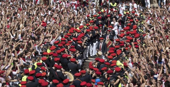 Cientos de personas alzan sus brazos al son de la música de los gaiteros que salen desde el Ayuntamiento de Pamplona para amenizar las calles del Casco Viejo de la ciudad tras el lanzamiento del tradicional chupinazo que ha abierto a las doce del mediodía