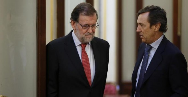 El presidente del Gobierno, Mariano Rajoy (i), conversa con el portavoz del PP en el Congreso, Rafael Hernando, en los pasillos de la Cámara Baja. /EFE