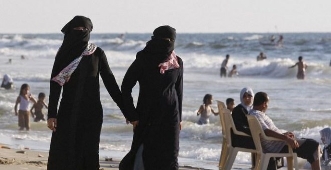 Dos mujeres con velo islámico en una playa.