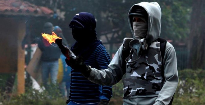 Manifestantes opositores se enfrentan a agentes de la Guardia Nacional Bolivariana mientras bloquean una calle en rechazo a las elecciones de la Asamblea Nacional Constituyente, en Barquisimeto. EFE/Pascuale Giorgio