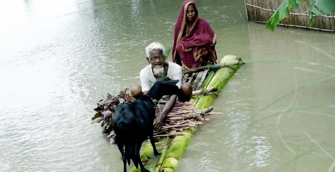 Una pareja bangladesí con una cabra navegan por las aguas de una gran inundación en el sur del país en busca de refugio AFP PHOTO/ Farjana K. GODHULY