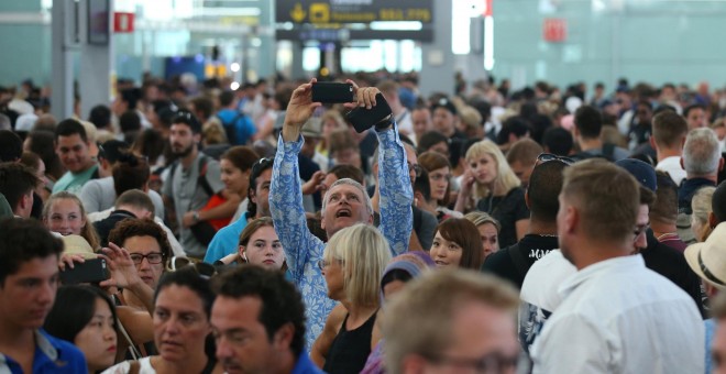 Un hombre toma una foto con su smartphone de las largas colas de pasajeros en los controles de seguridad del aeropuerto de Barcelona-El Prat, en la primera jornada de paros de los trabajadores de Eulen, encargada de este servicio. REUTERS/Albert Gea