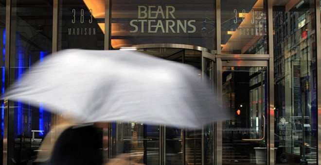 Una mujer con paraguas pasa junto a la entrada a la sede de Bear Stearns en Nueva York. AFP