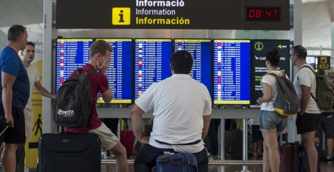 Varios viajeros consultan lo vuelos en los monitores del Aeropuerto de Barcelona-El Prat. EFE/Quique García