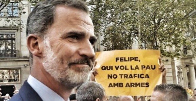 Imagen recogida de Twitter en la que Felipe VI pasa justo por delante de un de un manifestante que sujeta una pancarta con el lema: 'Quien hace la paz no trafica con armas'.