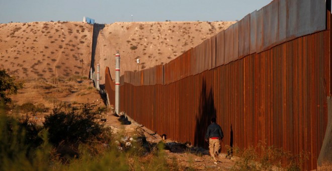 Un hombre pasa por una sección del muro que separa EEUU de México, cerca de Ciudad Juarez. - REUTERS