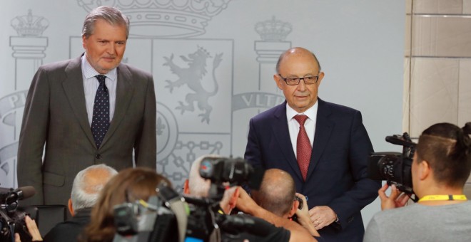 El portavoz del Gobierno y ministro de Educación, Cultura y Deporte, Íñigo Méndez de Vigo (i), y el ministro de Hacienda, Cristóbal Montoro, durante la rueda de prensa posterior a la reunión del Consejo de Ministros celebrada en el Complejo de La Moncloa.