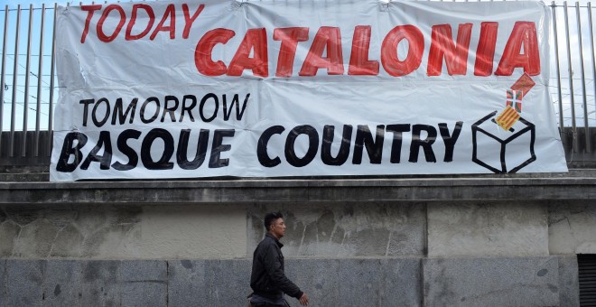 Un hombre pasea a su perro junto a una pancarta en la que se lee 'Hoy, Catalunya, mañana, el País Vasco', en Bilbao, durante la manifestacón por el derecho a decidir organizada por Gure Esku Dago. REUTERS/Vincent West