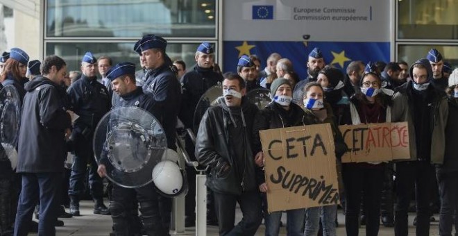 Policías belgas vigilan a los manifestantes concentrados frente al edificio de la Comisión Europea, durante la cumbre UE_canadá de octubre de 2016 en la que se firmó el CETA. AFP/jOHN tHYS