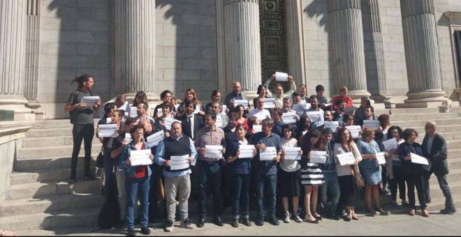 Los diputados portan carteles con el lema 'Detencions no, Democràcia sí' a las puertas del Congreso.