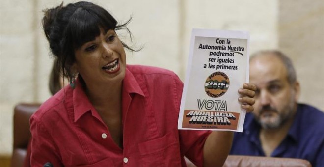 La portavoz de Podemos, Teresa Rodríguez, muestra un cartel en una de sus intervenciones durante la sesión de control al Gobierno que ha tenido lugar hoy en el Parlamento de Andalucía en Sevilla. /EFE