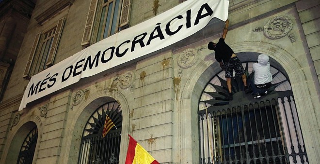 Dos personas intentan arrancar la pancarta de 'Mès Democràcia' colgada en el ayuntamiento de Barcelona EFE/Juan Carlos Cárdenas