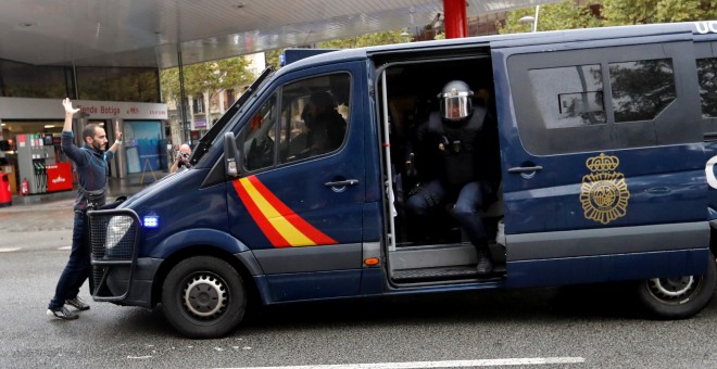 Un manifestante se coloca delante de una furgoneta de la Policía Nacional cerca de un colegio electoral en Barcelona durante el referéndum del 1-O. REUTERS/Yves Herman