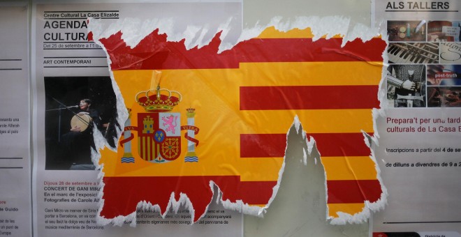 Una pegatina dañada de la bandera española junto a la catalana en una pared. / Reuters