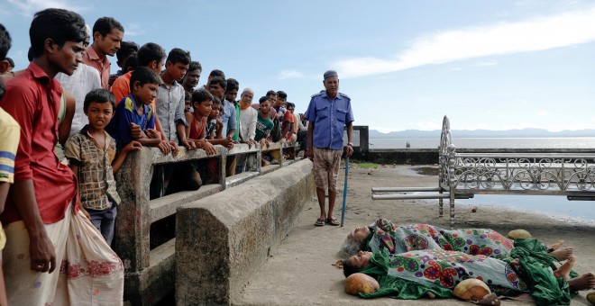 Varias personas observan los cadáveres de los refugiados rohinyás fallecidos este lunes en Bangladesh. /REUTERS