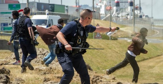 Fotografía de junio de 2015 de un policía gaseando a un inmigrante en Calais. - AFP