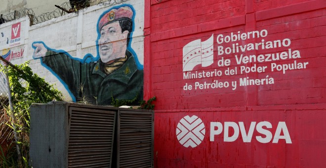 El logo de la compañía estatal venezolana de petroleo, PDVSA, junto a un mural de Hugo Chávez.REUTERS/Carlos García Rawlins