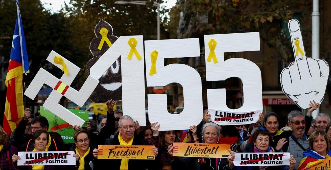 Varias personas con carteles contra la aplicación del artículo 155 de la Constitución, en la manifestacin para pedir la libertad de los líderes de ANC y Ômnium Cultural, Jordi Sánchez y Jordi Cuixart. REUTERS/Javier Barbancho