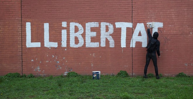 Un hombre pinta en un muro la palabra 'LLIBERTAD' en Barcelona.REUTERS/Albert Gea